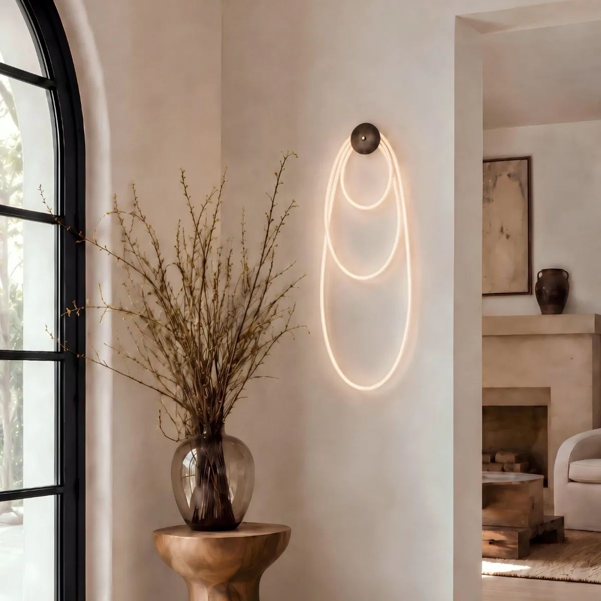 Selene wall fixture with illuminated cord looped in three nested ovals from a single dome canopy, on a plaster wall beside an arched window