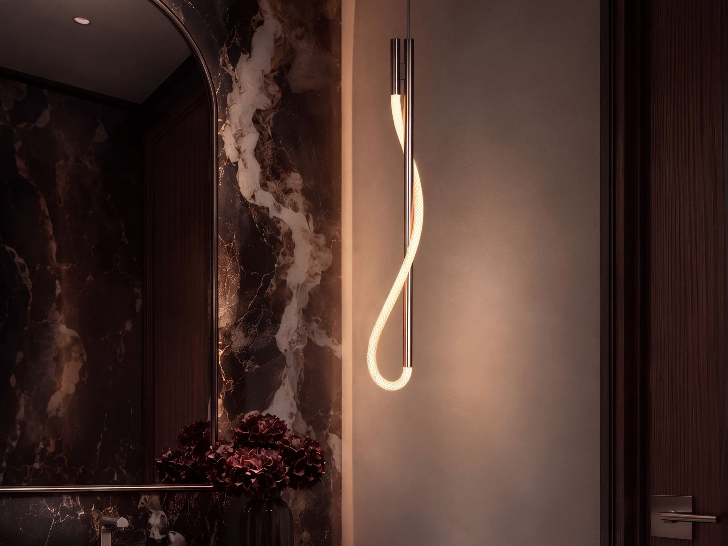 Eden pendant in satin nickel, illuminated cord looped around a slim vertical stem beside a marble vanity
